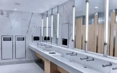 AquaGUARD solid surface trough sink module with trash cutout in commercial restroom.